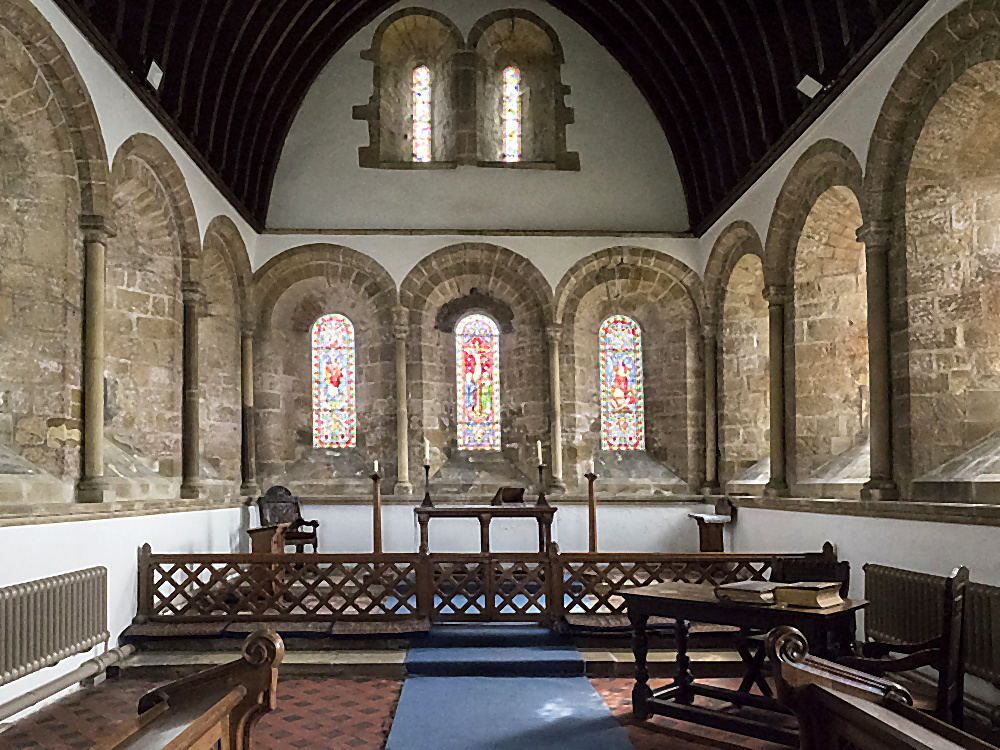 The 12th-century chancel of St Oswald's with its Norman round-arched windows, stained glass, and stone arcades