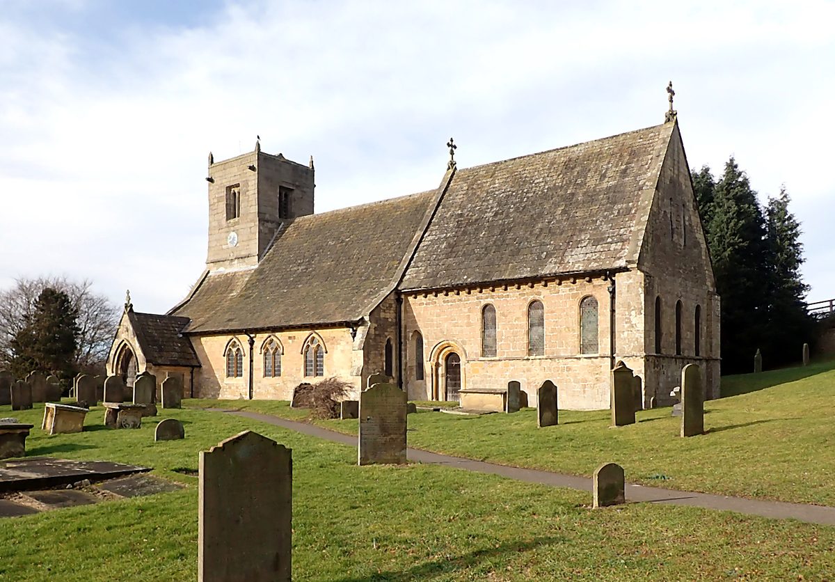 St Oswald's from the south-east on a bright winter morning, showing the gritstone tower, south porch, and surrounding gravestones