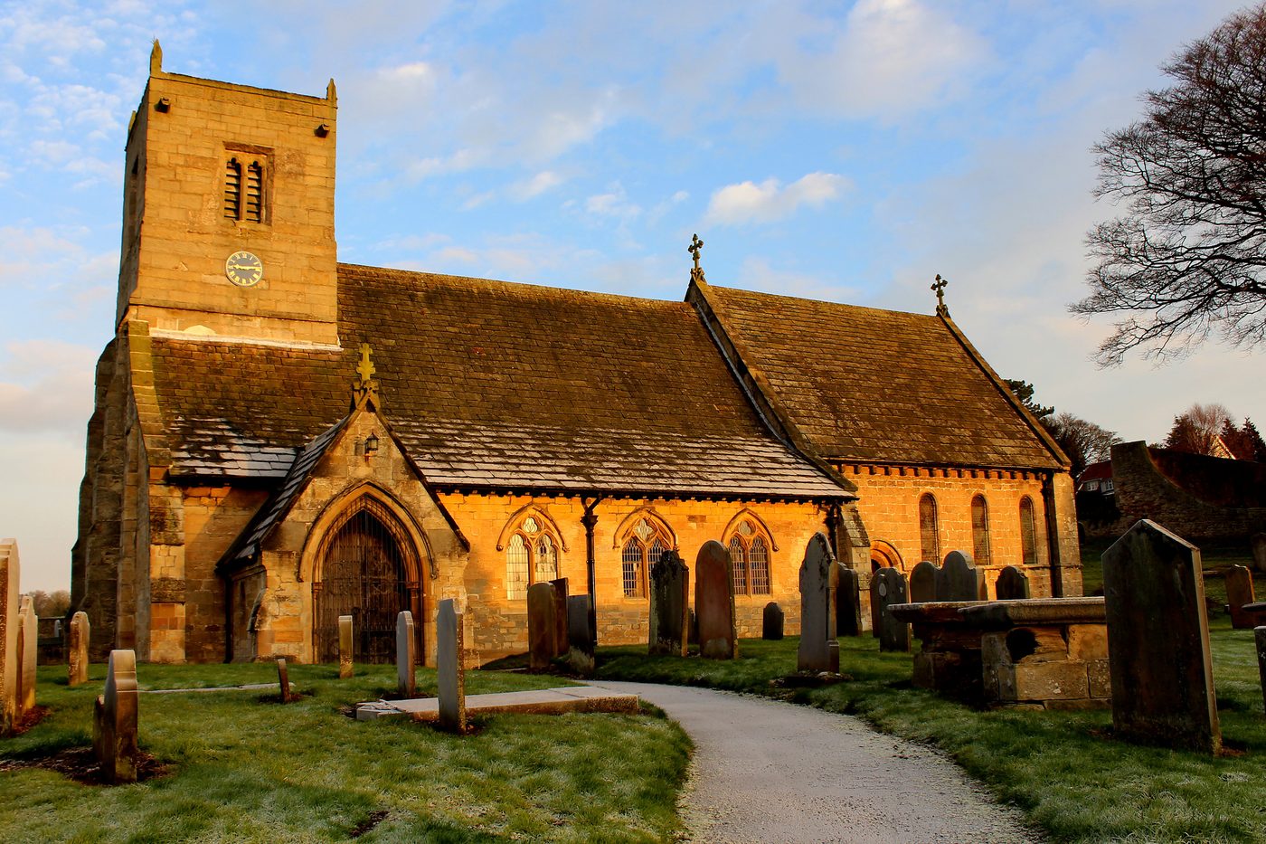 St Oswald's bathed in golden hour light, viewed from the south-west across the churchyard