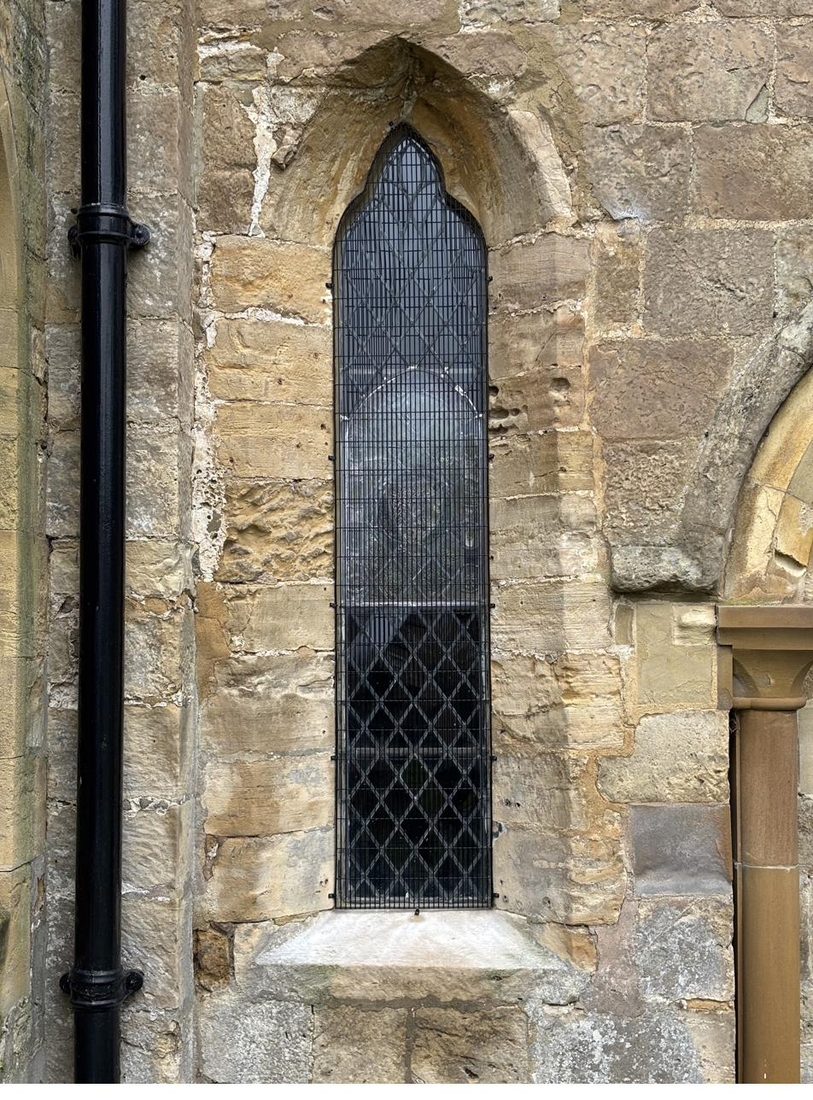 The chancel window from outside St Oswald's Church after restoration, with the new protective glazing and replacement outer grill in place